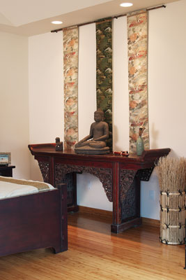 From the bedroom wall, vintage obi hang above an antique Chinese table and statue.